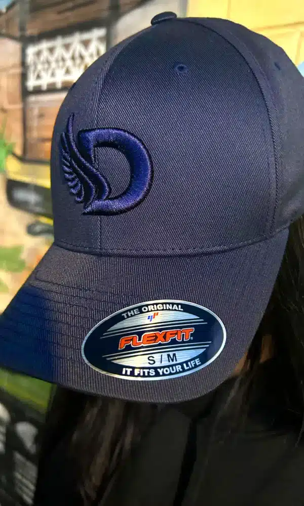 Front view of a woman wearing the DROW Navy FlexFit Cap featuring the iconic Embrodered D logos.